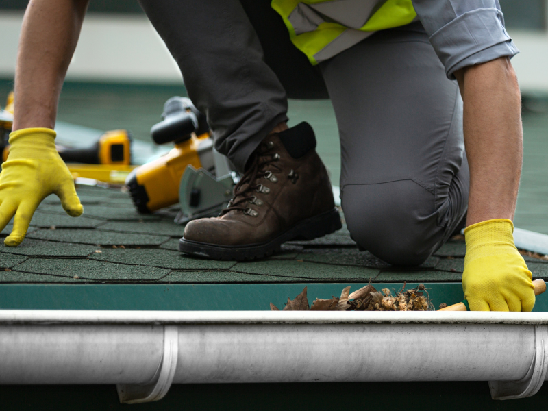 Technician unclogging a gutter that is full of leaves